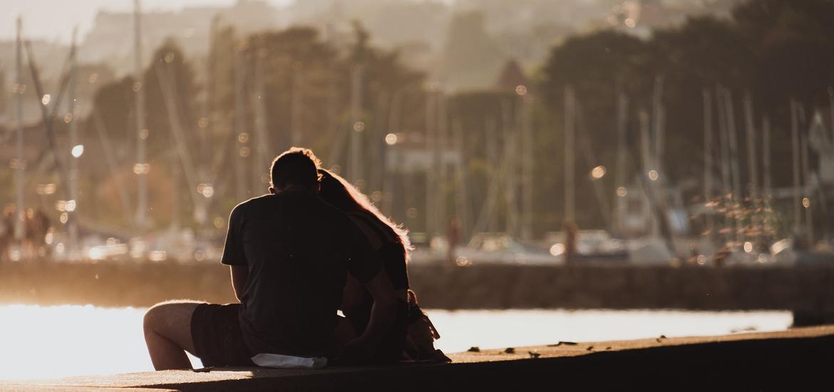 Couple embracing by a waterfront.